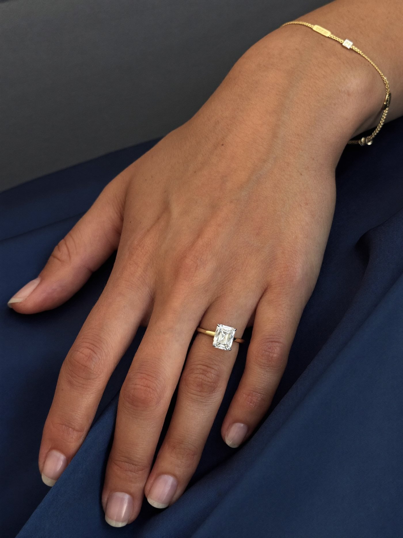 A hand wearing a diamond ring and a fine gold bracelet